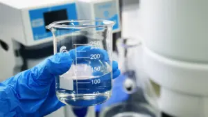 Laborants pārbauda ūdens kvalitāti laboratorijas stikla mērglāzē ar speciālu aprīkojumu.