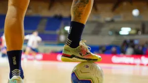 Sportists basketbola laukumā, gatavojoties spēlei ar bumbu, iekštelpu sporta hallē.